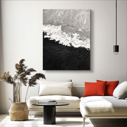 "Hand-painted Portrait shaped abstract textured wall art named 'Untamed Rift.' The artwork features a grey and black background separated by wild and expressive white strokes. The painting may symbolize a blend of elements or the conflict between water and fire. Hanging in the lounge."