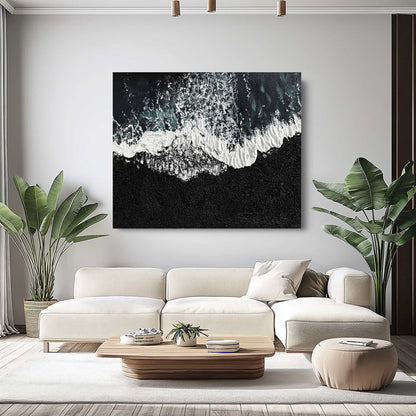 "BLACK BEACH, STYLE B: Hand-painted Landscape shaped textured wall art painting depicting a black beach with crashing waves, hanging in the living room, in shades of black, white, blue, green and grey."